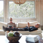 55+ couple using their phone and tablet on couch