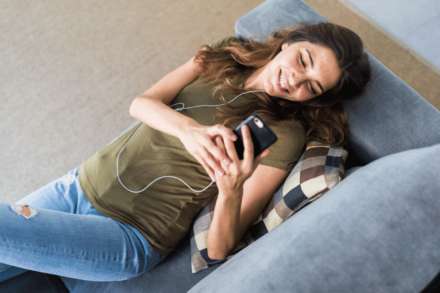Woman laying on couch watching videos on her phone