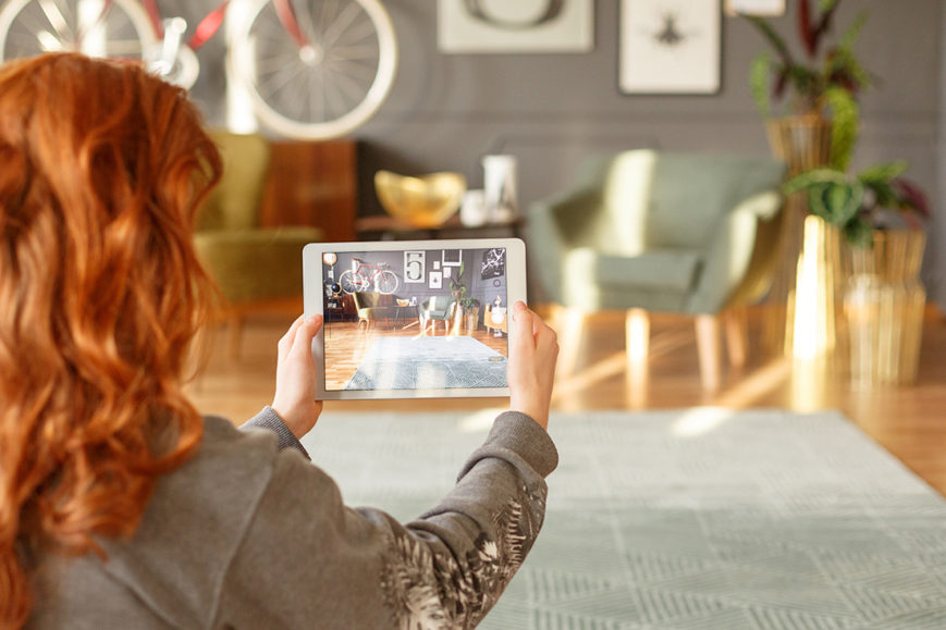 A woman uses a tablet to take images of a model home.