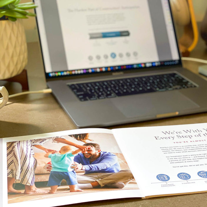 Laptop and coffee with open pamphlet on homebuying