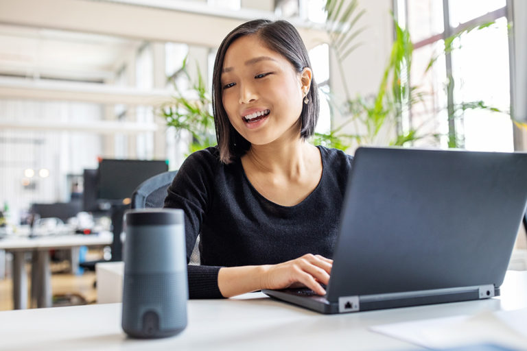 Businesswoman talking to virtual assistant at her desk.